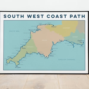May include: A map of the South West Coast Path in England, showing the coastline of Cornwall and Devon. The map is printed on a light blue background with a dark blue line representing the path. The map is framed in black.