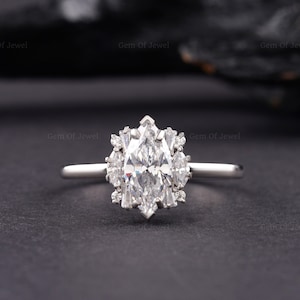 May include: A pear-shaped diamond engagement ring with a halo of smaller diamonds set in a white gold band.
