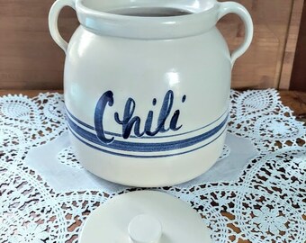 May include: White ceramic jar with blue stripes and the word "Chili" written on the front. The jar has two handles and a white lid.