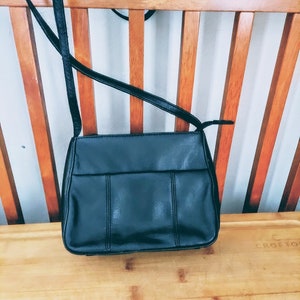 May include: A black leather crossbody bag with a flap closure and a long adjustable strap.