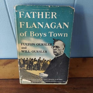 May include: A vintage book cover with a blue background and the title "Father Flanagan of Boys Town" in white text. The cover features a black and white photo of a man in a priest's collar, surrounded by a group of boys.