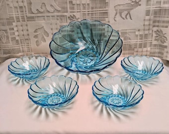 May include: A set of five light blue glass bowls. The set includes a large serving bowl and four smaller bowls. The bowls have a spiral design and a scalloped edge. The bowls are arranged on a white surface.