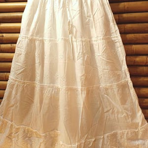 May include: A white tiered skirt with eyelet detailing and a drawstring waist. The skirt is made of a lightweight fabric and has a flowing, feminine silhouette. The skirt is approximately 36 inches long.