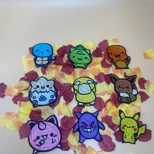 May include: Nine embroidered iron-on patches featuring various Pokemon characters. The patches are colourful and feature a variety of characters, including Pikachu, Squirtle, Bulbasaur, Charmander, and more.