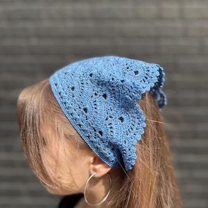 Könnte beinhalten: Ein blaues Häkelband mit einem zarten Muster. Das Stirnband wird von einer Person mit langen braunen Haaren getragen.