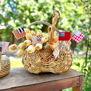 May include: A wicker basket filled with peach-colored silk flowers, decorated with small fabric flags in red, white, and blue.