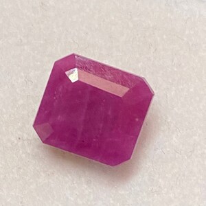 Op de afbeelding: Een levendige roze edelsteen met een rechthoekige, gefacetteerde vorm.