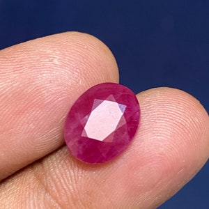 Op de afbeelding: Een levendige rode ovale edelsteen met een facetgeslepen vorm.