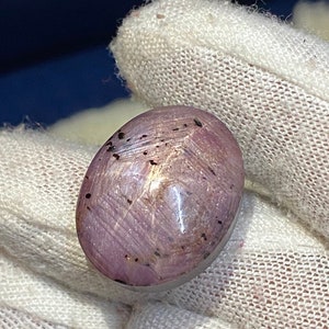 May include: A pink oval-shaped gemstone with black inclusions. The gemstone is set in a silver ring.