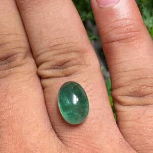 May include: A vibrant green oval-shaped gemstone with a smooth, polished surface.