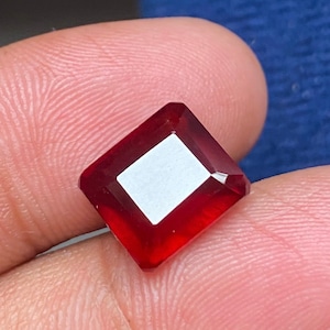 Op de afbeelding: Een vierkante, dieprode edelsteen met een facetgeslepen vorm.