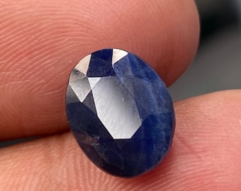 May include: A deep blue oval-shaped gemstone with a faceted cut.