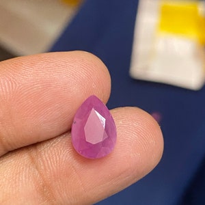 May include: A pear-shaped pink gemstone with a faceted cut.