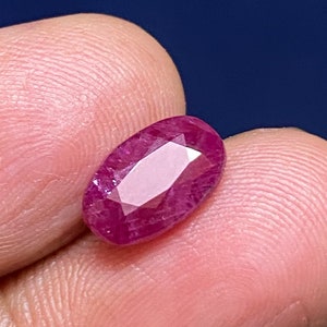 May include: A deep red oval-shaped gemstone with a faceted cut.