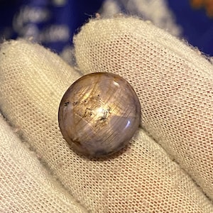 Peut inclure: Une pierre précieuse ronde et irisée avec une teinte violette claire et un motif en forme d'étoile. La pierre précieuse est sertie dans une bague en argent.