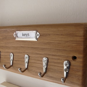 May include: Wooden key holder with five hooks and a metal label that says "keys".