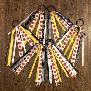 May include: Set of five hair ties with multiple ribbons attached. The ribbons are black, white, yellow, and have a basketball print.
