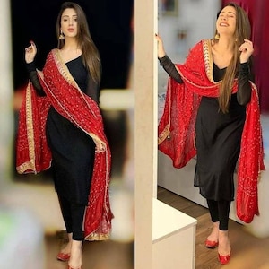 Peut inclure: Une femme portant un haut noir &agrave; manches longues avec un dupatta rouge et or. Le dupatta a une bordure dor&eacute;e et des broderies rouges et dor&eacute;es. La femme porte un legging noir et des chaussures rouges.
