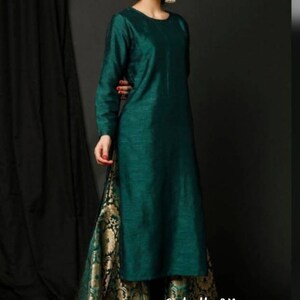 Op de afbeelding: Een tealgroene, langarmige kurta met een ronde halslijn, gecombineerd met gouden en groene brokaat palazzo-broeken. De outfit is gestyled met gouden oorbellen en de tekst "LabelbyKiara" is zichtbaar onderaan de afbeelding.