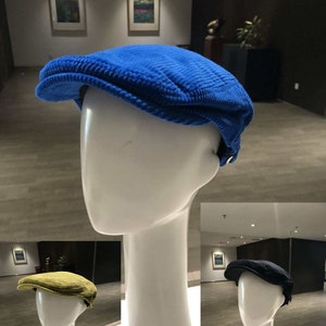 Può includere: Tre cappelli da golf in velluto a coste di diversi colori: blu, giallo e nero. I cappelli sono esposti su manichini.