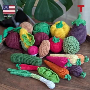 May include: A collection of crocheted vegetables, including a purple aubergine, a yellow pepper, a green cabbage, a red tomato, a green pea pod, a brown corn, a red beetroot, a pink radish, a green cucumber, a brown potato, and orange and pink carrots.  The vegetables are arranged on a wooden surface.  PDF file.