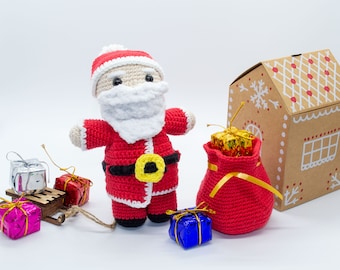 May include: A crocheted Santa Claus doll with a red suit, white beard, and yellow belt, holding a red bag filled with a gold wrapped gift. There are several wrapped gifts in the image, including a silver gift box on a wooden sled.