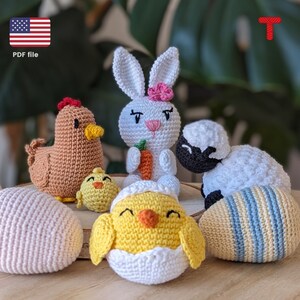 Puede incluir: Un conjunto de juguetes de animales de crochet para Pascua, que incluye un conejito, un pollito, un cordero y una gallina. Los juguetes están sentados sobre una superficie de madera con huevos de crochet.