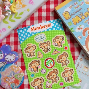 May include: A rectangular sticker sheet titled Monkeys! featuring various cartoon monkey illustrations on a bright green background with white stars. The sheet includes a speech bubble saying Me + my monkey! and a circular sticker that reads Fresh!! with a banana.