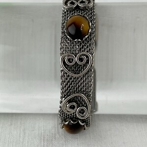 May include: Silver bracelet with a chain link design and brown tiger's eye stones.
