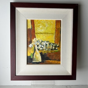 Può includere: Un dipinto a olio in una cornice marrone scuro. L'opera raffigura un vaso di fiori bianchi davanti a uno sfondo giallo. Il dipinto ha uno stile impressionista strutturato, con pennellate visibili e una calda tavolozza di colori.