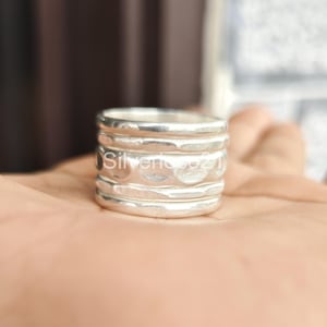 K&ouml;nnte beinhalten: Ein silberner Ring mit geh&auml;mmerter Textur und mehreren B&auml;ndern. Der Ring ist aus Sterlingsilber gefertigt und hat eine einzigartige, handgefertigte Optik.