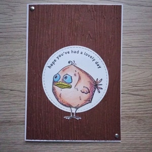 Pájaro marrón de papel A6 hecho a mano. Espero que hayas tenido un día encantador. Pájaro pardo. Fondo de madera. Pájaro triste. Ojos brillantes y pico. Sobre incluido