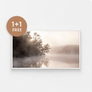 Könnte beinhalten: Eine nebelige Seenszene mit einem einzelnen Baum im Vordergrund und einem Wald im Hintergrund. Die Sonne scheint durch den Nebel und erzeugt einen weichen, ätherischen Schein.