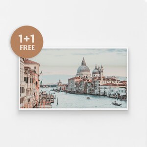 May include: A panoramic view of a canal in Venice, Italy. The water is calm and reflects the sky. Buildings line the canal, including a large church with a dome. Gondolas and other boats are visible in the water.