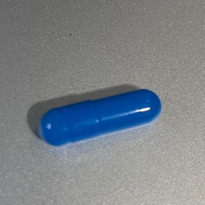 May include: A single blue capsule pill.