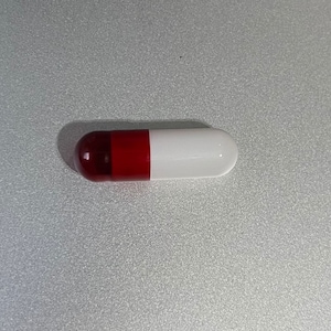 May include: A red and white capsule pill.