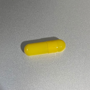 May include: A single yellow capsule pill.
