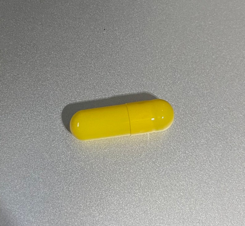 May include: A single yellow capsule pill.