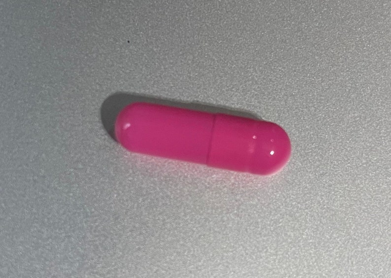 May include: A single pink capsule pill.