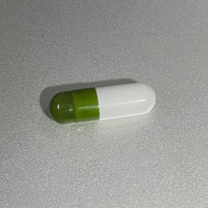 May include: A green and white capsule pill.