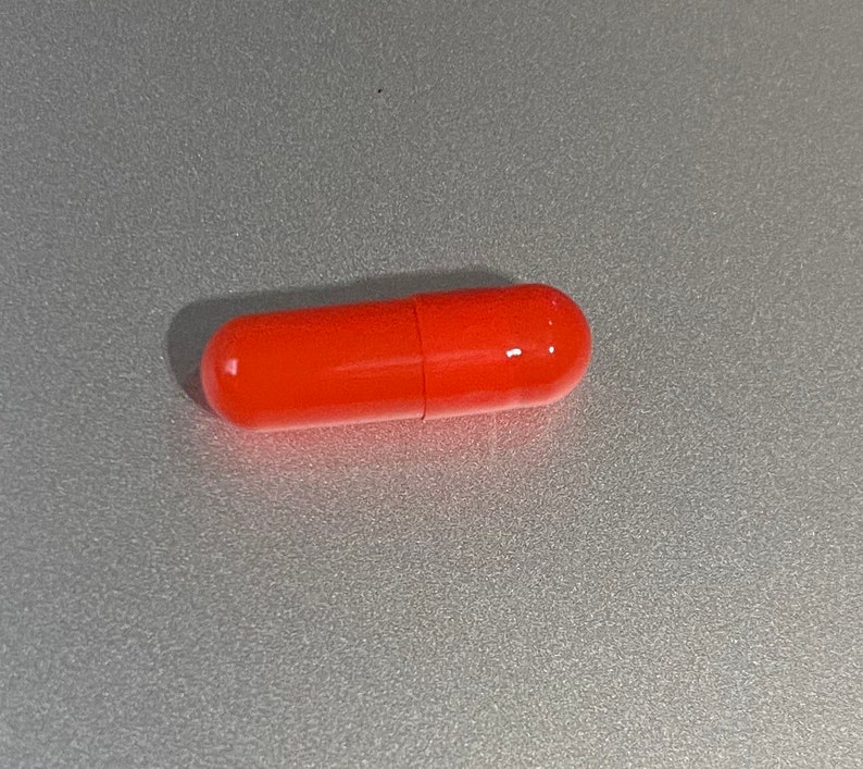 May include: A single bright orange capsule pill.