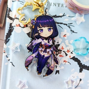 May include: A purple and white anime character keychain with a gold chain. The character has long purple hair, a white and purple outfit, and a blue and purple background.