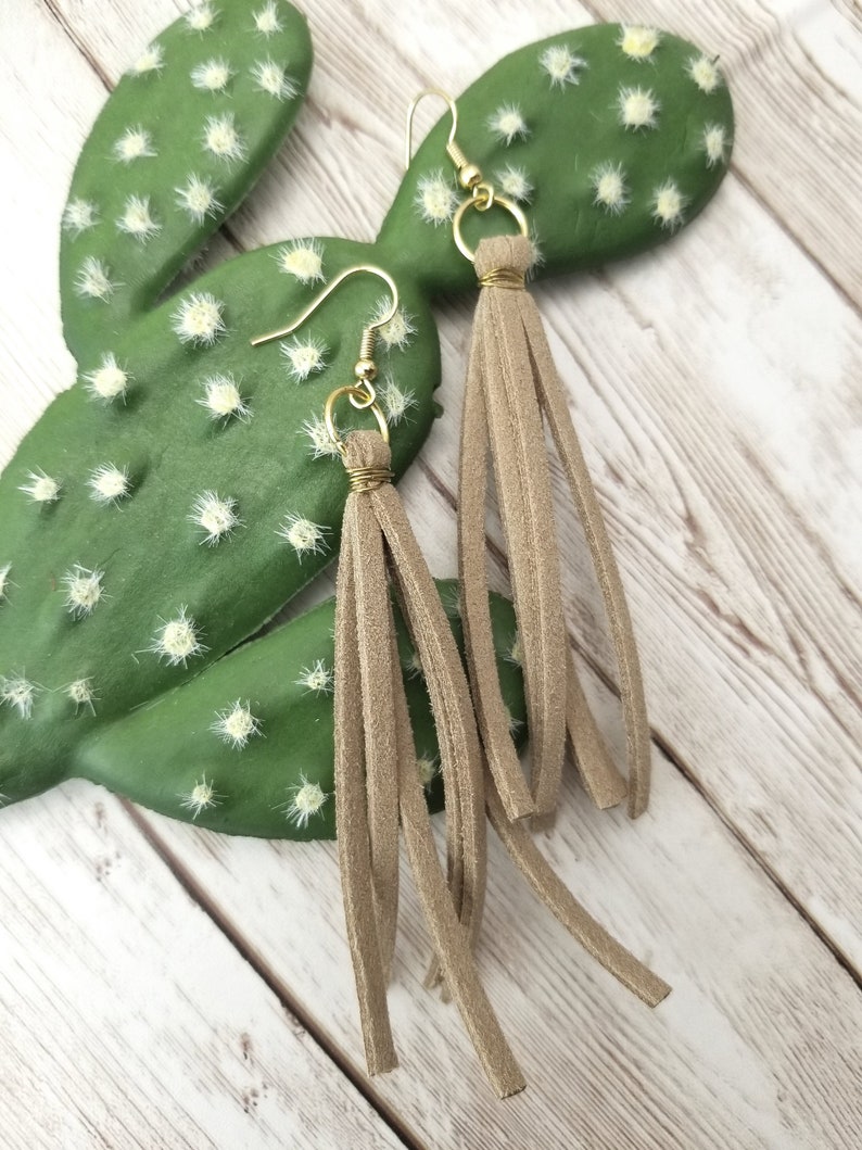 May include: A pair of brown suede tassel earrings with gold-toned hoops and wire wraps.