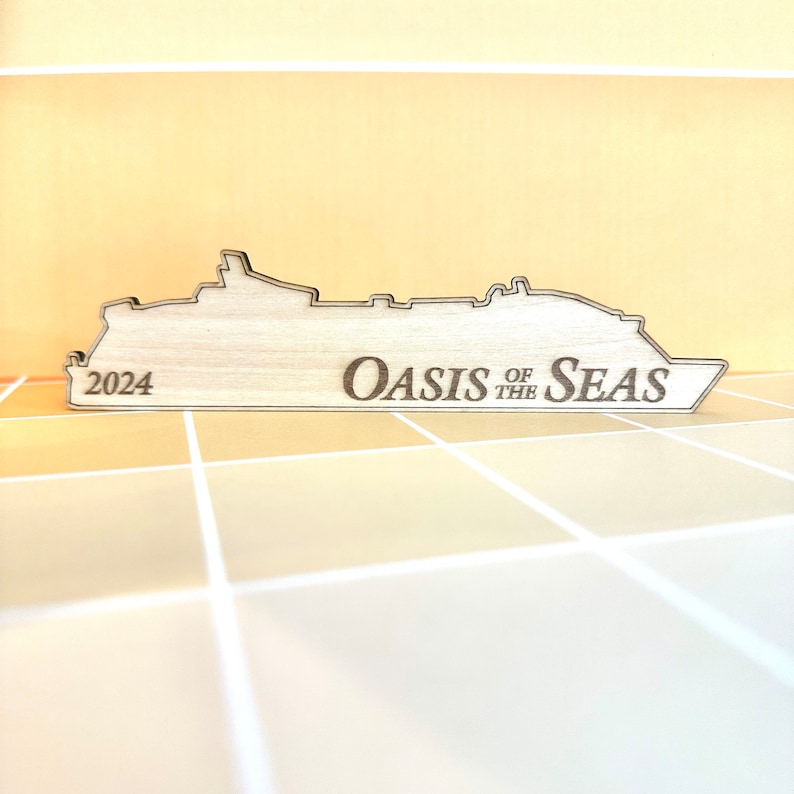K&ouml;nnte beinhalten: Ein Holzausschnitt eines Kreuzfahrtschiffs mit dem Text "Oasis of the Seas" und "2024" darauf.
