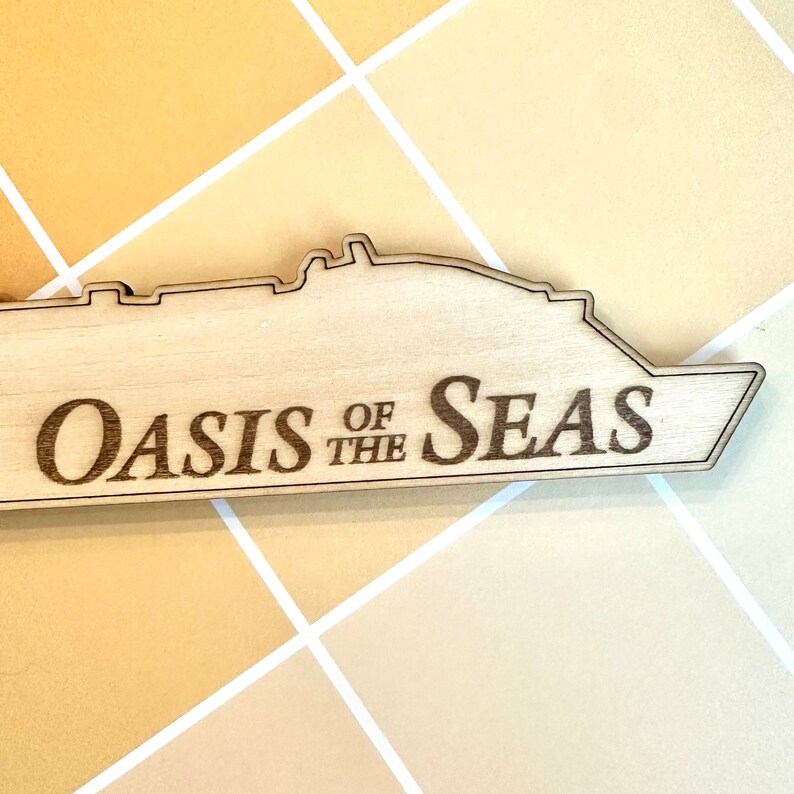 K&ouml;nnte beinhalten: Ein Holzausschnitt eines Kreuzfahrtschiffs mit dem eingravierten Text "Oasis of the Seas".