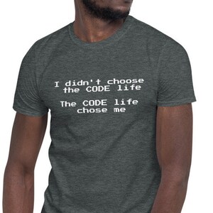 Może przedstawiać: Ciemnoszara koszulka z białym napisem: "I didn't choose the CODE life, The CODE life chose me". Koszulka ma krótki rękaw i okrągły dekolt.