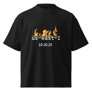 Puede incluir: Camiseta negra con cuello alto y mangas cortas. La camiseta presenta un gráfico de llamas en amarillo, naranja y rojo, con el texto "us-east-1" en verde y la fecha "10.20.25" en blanco.