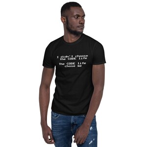 以下が含まれることがあります： 「I didn't choose the CODE life, The CODE life chose me」の白文字がプリントされた黒いTシャツ。半袖クルーネックのスタイルです。