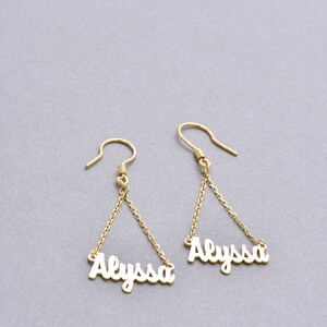May include: Gold dangle earrings with the name "Alyssa" spelled out on each earring.