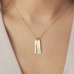 Peut inclure: Collier en or avec quatre pendentifs en forme de barre verticale, chacun gravé d'un nom : "Margaret", "Queen", "Dylan".